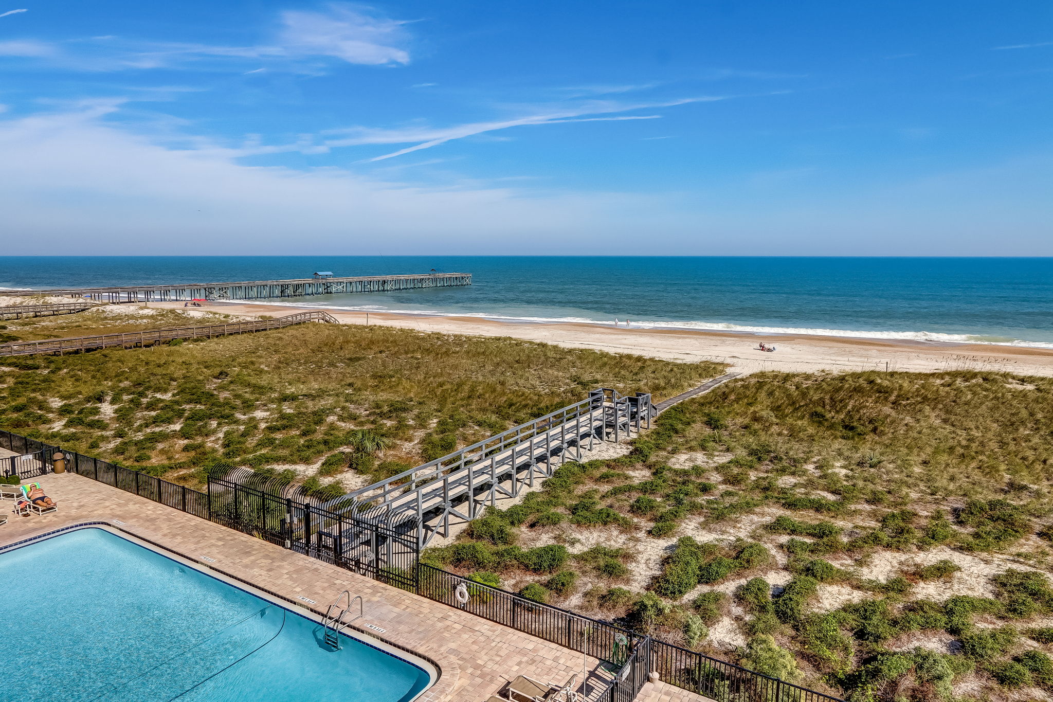 View from above showing the community pool, dunes, boardwalk to beach, and the fishing pier